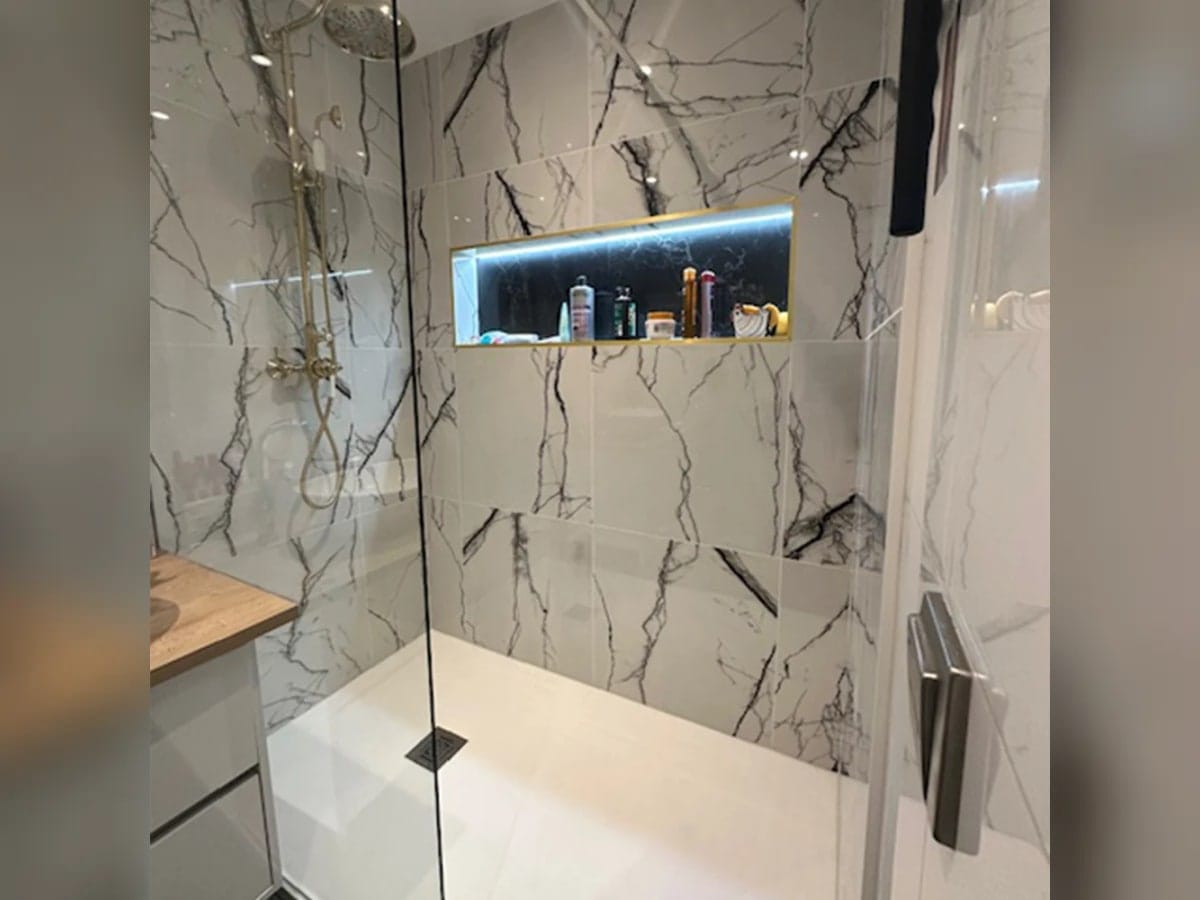 Salle de bain marbre clair avec barres de maintien PMR